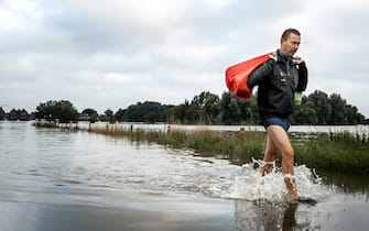 epa09349771 A man leaves a flooded house in evacuated Arcen, North Limburg, The Netherlands, 17 July 2021.  Heavy rainfall has led to floods and damages in various parts of the Netherlands and western Europe.  EPA/REMKO DE WAAL