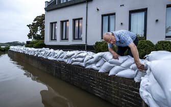 epa09349770 A resident of the evacuated Arcen looks at the rising water of the river Maas, in Arcen, North Limburg, The Netherlands, 17 July 2021.  Heavy rainfall has led to floods and damages in various parts of the Netherlands and western Europe.  EPA/REMKO DE WAAL