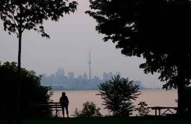 TORONTO, CANADA - JULY 19:  A woman waits to watch the sun rise above the CN Tower on July 19, 2021 in Toronto, Canada. (Photo by Gary Hershorn/Getty Images)