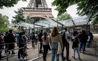 Visitors wait in line as they arrive to visit the Eiffel Tower in Paris, on July 16, 2021. - The Eiffel Tower reopened to visitors on July 16, 2021, after nine months of shutdown caused by the Covid pandemic. Up to 13,000 people per day will be allowed to take the elevators to the top and take in the views over the French capital, down from 25,000 in the pre-Covid era. (Photo by Bertrand GUAY / AFP) (Photo by BERTRAND GUAY/AFP via Getty Images)