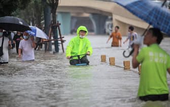This photo taken on July 20, 2021 shows a man riding a bicycle through flood waters along a street following heavy rains in Zhengzhou in China's central Henan province. - - China OUT (Photo by STR / AFP) / China OUT (Photo by STR/AFP via Getty Images)