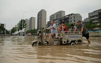 People wade through a flooded street following a heavy rain in Zhengzhou, in China's Henan province on July 22, 2021. (Photo by Noel Celis / AFP) (Photo by NOEL CELIS/AFP via Getty Images)