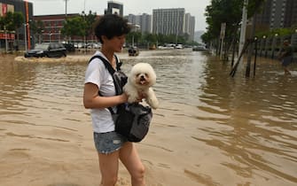 1234104865 People wade through a flooded street following a heavy rain in Zhengzhou, in China's Henan province on July 22, 2021. (Photo by Noel Celis / AFP) (Photo by NOEL CELIS/AFP via Getty Images)