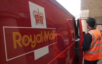 Un postino della Royal Mail davanti al furgone del servizio postale britannico