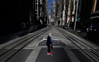 Una cittadina attraversa una strada a Sydney, durante il lockdown per l'emergenza Covid