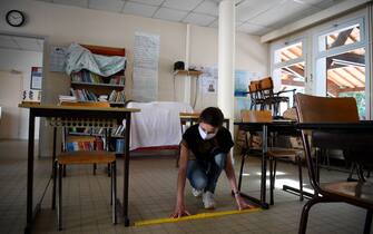 1212095494 TOPSHOT - French school director Delphine Bediou sets up a classroom to mark social distancing measures at an elementary school, a few days before its reopening, in Clairefontaine-en-Yvelines, on May 7, 2020, on the 52nd day of a strict lockdown in the country aimed at curbing the spread of the COVID-19 (the novel coronavirus). - Primary schools and daycare centres are scheduled to reopen gradually from May 11 in France, then junior high schools the following week -- but only in areas not hit hard by the epidemic, as the country prepares to ease a two-month coronavirus lockdown. (Photo by FRANCK FIFE / AFP) (Photo by FRANCK FIFE/AFP via Getty Images)