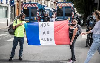 FRANCE CORONAVIRUS PANDEMIC VACCINATION PROTEST epa09382552 Protesters hold a french flag reading 'No to the Pass' during a demonstration against the COVID-19 health pass which grants vaccinated individuals greater ease of access to venues in France, in Paris, France, 31 July 2021. Anti-vaxxers, joined by the anti-government 'yellow vest' movement, are demonstrating across France for the third consecutive week in objection to the health pass, which is now mandatory for people to visit leisure and cultural venues. EPA/CHRISTOPHE PETIT TESSON