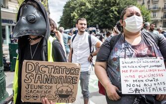 epa09382550 A protester holds a poster reading 'Sanitary Dictature, Youngness sacrified' during a demonstration against the COVID-19 health pass which grants vaccinated individuals greater ease of access to venues in France, in Paris, France, 31 July 2021. Anti-vaxxers, joined by the anti-government 'yellow vest' movement, are demonstrating across France for the third consecutive week in objection to the health pass, which is now mandatory for people to  visit leisure and cultural venues.  EPA/CHRISTOPHE PETIT TESSON