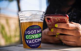 WASHINGTON, D.C. - MAY 06: Tamaria Kelly, 34, drinks a free beer after receiving a COVID-19 vaccine at the DC Health Department's Take the Shot, DC, walk-up clinic held at the John F. Kennedy Center for the Performing Arts' outdoor Victura Park at the REACH on Thursday, May 06, 2021 in Washington, D.C. Attendants were provided with a single dose of the Johnson & Johnson vaccine and offered a free beer, courtesy of Solace Brewing Co., as part of D.C.s Vaxed for Mom initiative. (Photo by Amanda Voisard/for The Washington Post via Getty Images)