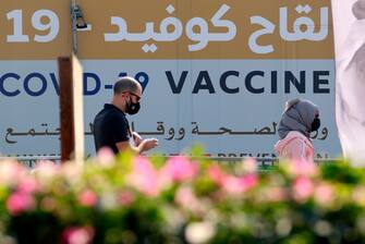 A man and a woman walk past a huge health ministry COVID-19 vaccines announcement outside a medical centre in Dubai on February 16, 2021, as the Gulf emirates goes ahead its vaccination effort. - The UAE, home to a population of around 10 million, has administered some 4.6 million doses of vaccine, making it the second-fastest per capita delivery in the world, after Israel. (Photo by Karim SAHIB / AFP) (Photo by KARIM SAHIB/AFP via Getty Images)