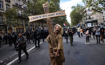 epa09404309 A protester dressed as Jesus holds a cross bearing the message 'the vaccine kills your immune system', during a demonstration against the COVID-19 health pass which grants vaccinated individuals greater ease of access to venues in France, in Paris, France, 07 August 2021. The national enforcement of the 'Health Pass' is expected to take effect on 09 August, after the French Constitutional Council has confirmed the government's law which extend the use of its Vaccinal Passeport (a QR code which proves the bearer has received full vaccination, or been tested negative for Covid in the last 72 hours) to cultural place, transport, and restaurants among other places.  EPA/IAN LANGSDON