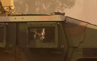 epa09404938 A member of the National Guard puts on an N95 mask at the Dixie Fire near Greenville, California, USA, 07 August 2021. The Dixie Fire had grown to over 440,000 acres as of 07 August.  EPA/CHRISTIAN MONTERROSA