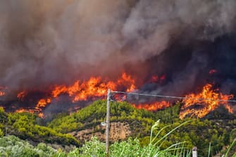 1234458408 A forest fire engulfs the forest of a mountain side in the area of Platanos village, near ancient Olympia in western Greece on August 4, 2021. - Greek firefighters have been battling several heatwave-fuelled forest infernos, including around Athens that have destroyed or damaged dozens of homes and businesses and forced the evacuation of villages, and others in the south and on the island of Euboea. (Photo by STR / Eurokinissi / AFP) (Photo by STR/Eurokinissi/AFP via Getty Images)
