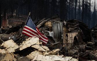 GREENVILLE, CA - AUGUST 08: An American flag is placed amidst the rubble on August 8, 2021 in GREENVILLE, California. On July 5, 2021 the Dixie Fire swept through Greenville, California destroying homes, historic buildings and forcing hundreds to evacuate. (Photo by Maranie R. Staab/Getty Images)