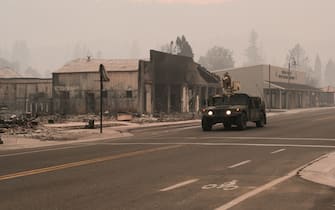 GREENVILLE, CA - AUGUST 08: A U.S. National Guard humvee drives along Highway 89 past burned structures destroyed by the Dixie Fire on August 8, 2021 in Greenville, California. The Dixie Fire, which has incinerated more than 463,000 acres, is the second largest recorded wildfire in state history and remains only 21 percent contained. (Photo by David Odisho/Getty Images)