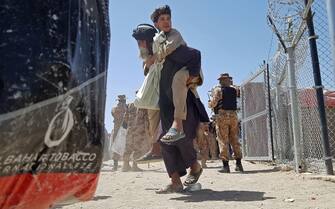 A stranded Afghan national carries his son at the Pakistan-Afghanistan border crossing point in Chaman on August 13, 2021, after the Taliban took control of the Afghan border town in a rapid offensive across the country. (Photo by - / AFP) (Photo by -/AFP via Getty Images)