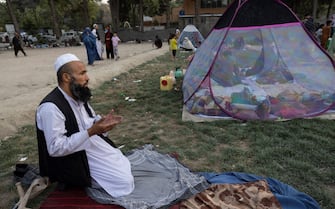 1234636843 KABUL, AFGHANISTAN - AUGUST 12: Sayed Amanullah from Kunduz prays at a makeshift IDP camp in Share-e-Naw park to various mosques and schools on August 12, 2021 in Kabul, Afghanistan. People displaced by the Taliban advancing are flooding into the Kabul capital to escape the Taliban takeover of their provinces. (Photo by Paula Bronstein/Getty Images)