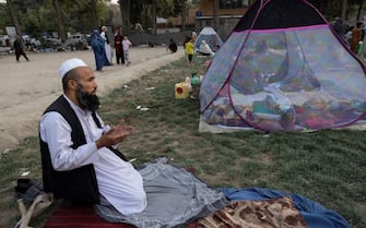 KABUL, AFGHANISTAN - AUGUST 12: Sayed Amanullah from Kunduz prays at a makeshift IDP camp in Share-e-Naw park to various mosques and schools on August 12, 2021 in Kabul, Afghanistan. People displaced by the Taliban advancing are flooding into the Kabul capital to escape the Taliban takeover of their provinces. (Photo by Paula Bronstein/Getty Images)