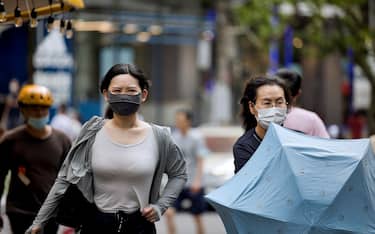 epa09400754 People wearing face masks walk on a street in Shanghai, China, 06 August 2021. The China National Health Commission on 06 August reported 124 new confirmed COVID-19 cases. It is the highest daily count in the current outbreak. Some 80 new locally transmitted cases were reported in Mainland China, of which 61 were recorded in the Jiangsu province the day befor on 05 August.  EPA/ALEX PLAVEVSKI