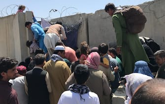 People struggle to cross the boundary wall of Hamid Karzai International Airport to flee the country after rumors that foreign countries are evacuating people even without visas, after the Taliban over run of Kabul, Afghanistan, 16 August 2021.  (Photo by STR/NurPhoto via Getty Images)
