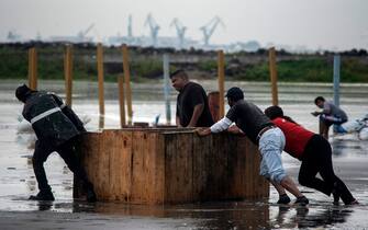 Workers remove furniture from the beach as strong waves reach the coast due to Hurricane Grace, which has reached category 2, in Boca del Rio, Veracruz, Mexico, on August 20, 2021. - Grace regained hurricane strength Friday as it barreled towards Mexico for a second time, triggering warnings of flooding and mudslides in mountains on the eastern mainland. (Photo by VICTORIA RAZO / AFP) (Photo by VICTORIA RAZO/AFP via Getty Images)
