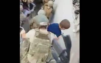 soldato turco mette in salvo un bambino