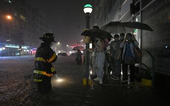 A member of the FDNY directs people stranded at a subway entrance during flash flooding caused by storm Ida in the New York City borough of Queens, NY, September 1, 2021. (Photo by Anthony Behar/Sipa USA)