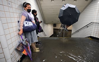 People stand inside a subway station as water runs past their feet during flash flooding caused by storm Ida in the New York City borough of Queens, NY, September 1, 2021. (Photo by Anthony Behar/Sipa USA)