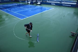 TOPSHOT - Court staff clean the rain off the courts at the USTA Billie Jean King National Tennis Center in New York, on September 1, 2021. - Outside court matches have been postponed as the remnants for Hurricane Ida pass through the region. (Photo by KENA BETANCUR / AFP) (Photo by KENA BETANCUR/AFP via Getty Images)