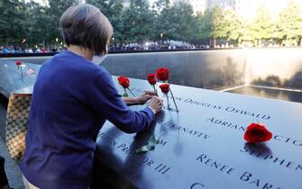 epa09461067 A woman places flowers on the 9/11 Memorial on the 20th anniversary of the September 11 attacks in Manhattan, New York City, U.S., September 11, 2021.  EPA/MIKE SEGAR / POOL
