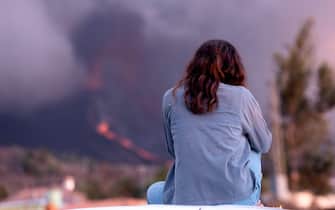epa09486857 A woman looks at a volcanic eruption after two new vents appeared expelling lava, in La Palma island, Canary Islands, southwestern Spain, 24 September 2021 (issued 25 September 2021). Residents from the three most threaten areas of the island had to be evacuated after the volcano registered more explosive eruptions and two new vents opened up. The Cumbre Vieja volcano began to erupt in the Montana Rajada mountains in the municipality of El Paso on 19 September. The area had registered hundreds of small earthquakes along the week as magma pressed the subsoil on its way out, urging the regional authorities to evacuate locals before the eruption took place.  EPA/MIGUEL CALERO