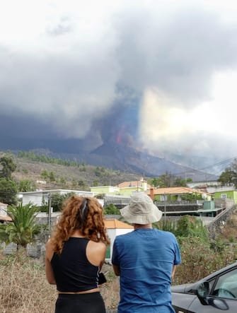epa09486096 People observe the new eruptive mouth on the Cumbre Vieja volcano in El Paso, La Palma, Canary Islands, Spain, 24 September 2021. People from Tajuya, Tacande de Arriba and Tacande de Abajo in La Palma have been evacuated due to the new activity of the volcano. The new volcano began to erupt in Rajada Mountain in the municipality of El Paso on 19 September. The area had registered hundreds of small earthquakes along the week as magma pressed the subsoil on its way out, urging the regional authorities to evacuate locals before the eruption took place.  EPA/Miguel Calero