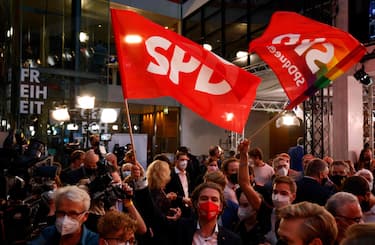 Supporters wave flags at the Social Democrats (SPD) headquarters after the exit polls were broadcast on television in Berlin on September 26, 2021 after the German general elections. (Photo by Odd ANDERSEN / AFP)