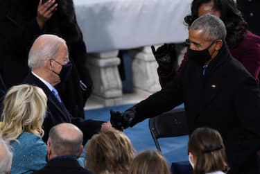 US President-elect Joe Biden (L) greets former US President Barack Obama, with a fist bump ahead of his inauguration as the 46th US President on January 20, 2021, at the US Capitol in Washington, DC. (Photo by OLIVIER DOULIERY / AFP)