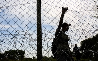 Refugees stand by a barbwire fence as Hungry closed the border line between Serbia and Hungary in Roszke, southern Hungary on September 15, 2015. A razor-wire barrier along the 175km border with Serbia is aimed at keeping out refugees entering from Serbia (Photo by Beata Zawrzel/NurPhoto via Getty Images)