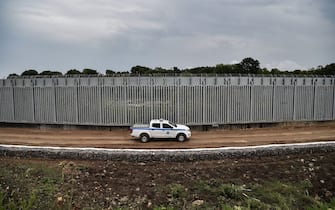 A police car patrols along a steel fence along Evros river, Greece's river border with Turkey, near the village of Poros on June 8, 2021. - The area is where the Greek State has chosen to deploy a new anti-migration arsenal including cameras, radar and a 40-kilometre (25-mile) steel fence over five metres high. (Photo by Sakis MITROLIDIS / AFP) (Photo by SAKIS MITROLIDIS/AFP via Getty Images)