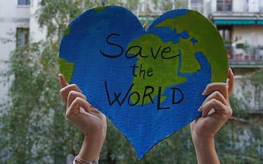 Milano - ragazza ambientalista protesta con cartello Save the wordl, per proteggere la il pianeta dall'inquinamento