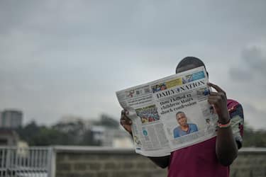 A man poses with Kenya's daily newspaper Daily Nation which carries headlines on a murderer involved in the deaths of at least 10 children in Nairobi on July 15, 2021. - Masten Milimo Wanjala, 20, was arrested on July 14 over the killing of two children whose bodies were found dumped in a forested area of the capital Nairobi. But in a chilling confession, he admitted to the cold-blooded killing of at least 10 young teenagers, police said. (Photo by SIMON MAINA / AFP) (Photo by SIMON MAINA/AFP via Getty Images)