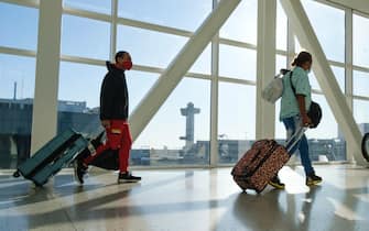 passeggeri in aeroporto con mascherina e valigie