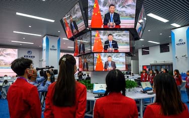 People watch screens showing live images of China's President Xi Jinping speaking during the opening ceremony of the China International Import Expo (CIIE), at the media center of the CIIE in Shanghai on November 4, 2021. - China OUT (Photo by AFP) / China OUT (Photo by STR/AFP via Getty Images)