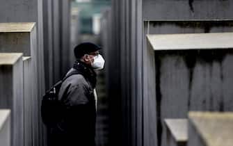 epa09578361 A man wearing a face mask walks between steles of the so-called Holocaust memorial, the Memorial to the murdered Jews of Europe in Berlin, Germany, 12 November 2021. Due to an increasing number of cases of the COVID-19 disease caused by the coronavirus SARS CoV-2, new nationwide restrictions has been announced to counter a surge in infections.  EPA/FILIP SINGER