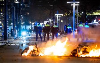 epa09593019 Policemen stand near burning objects after a protest against the '2G policy' turned into riots, with protesters setting fires in the street and destroying police cars and street furniture, Rotterdam, Netherlands, 19 November 2021. Hundreds of demonstrators gathered on Coolsingel earlier that evening because they disagree with the 2G policy, which refers to the two Dutch words for vaccinated and recovered.  EPA/VLN NIEUWS