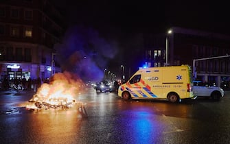 THE HAGUE, NETHERLANDS - NOVEMBER 20: An ambulance drives past bycicles and scooters set ablaze by a mob as riots erupt amid new Corona virus restrictions on November 20, 2021 in The Hague, Netherlands. (Photo by Pierre Crom/Getty Images)