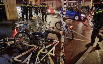THE HAGUE, NETHERLANDS - NOVEMBER 20: A man hit on the legg by the batton of a police officer falls on the ground between police bycicles as riots erupt amid new Corona virus restrictions on November 20, 2021 in The Hague, Netherlands. (Photo by Pierre Crom/Getty Images)