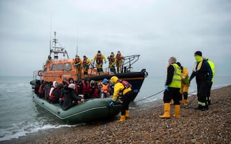 Migrants are helped ashore from a RNLI (Royal National Lifeboat Institution) lifeboat at a beach in Dungeness, on the south-east coast of England, on November 24, 2021, after being rescued while crossing the English Channel. - The past three years have seen a significant rise in attempted Channel crossings by migrants, despite warnings of the dangers in the busy shipping lane between northern France and southern England, which is subject to strong currents and low temperatures. (Photo by Ben STANSALL / AFP)