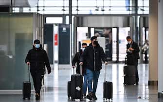 passeggeri in aeroporto con mascherina e valigie