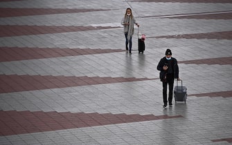 passeggeri in aeroporto con mascherina e valigie