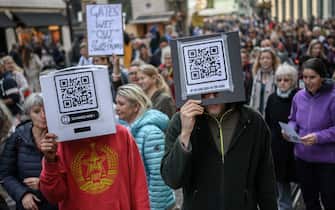 Protesters hold cardboard boxes reading in French 'Scan me' and 'Im not a QR code' during a rally against coronavirus measures, Covid-19 health pass and vaccination in Geneva on October 9, 2021. - On 28 November 2021, Swiss voters will be asked whether they accept laws passed by the government on 19 March 2021 that paved the way for the introduction of Switzerlands Covid certificate, a system that provides proof of vaccination, recovery or a negative test. (Photo by Fabrice COFFRINI / AFP) (Photo by FABRICE COFFRINI/AFP via Getty Images)
