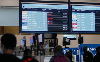 Travellers walk near an electronic flight notice board displaying cancelled flights  at OR Tambo International Airport in Johannesburg on November 27, 2021, after several countries banned flights from South Africa following the discovery of a new Covid-19 variant Omicron. - A flurry of countries around the world have banned ban flights from southern Africa following the discovery of the variant, including the United States, Canada, Australia,Thailand, Brazil and several European countries. The main countries targeted by the shutdown include South Africa, Botswana, eSwatini (Swaziland), Lesotho, Namibia, Zambia, Mozambique, Malawi and Zimbabwe. (Photo by Phill Magakoe / AFP) (Photo by PHILL MAGAKOE/AFP via Getty Images)