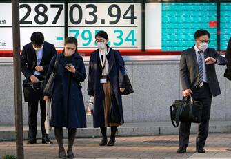 epaselect epa09604218 Passersby stand before a stock market indicator board in Tokyo, Japan, 26 November 2021. Tokyo stocks plunged following concerns as the global economy could be hit by a new COVID-19 variant. The 225-issue Nikkei Stock Average closed down 747.66 points, or 2.53 per cent, to end the week at 28,751.62, its lowest figure in a month.  EPA/FRANCK ROBICHON